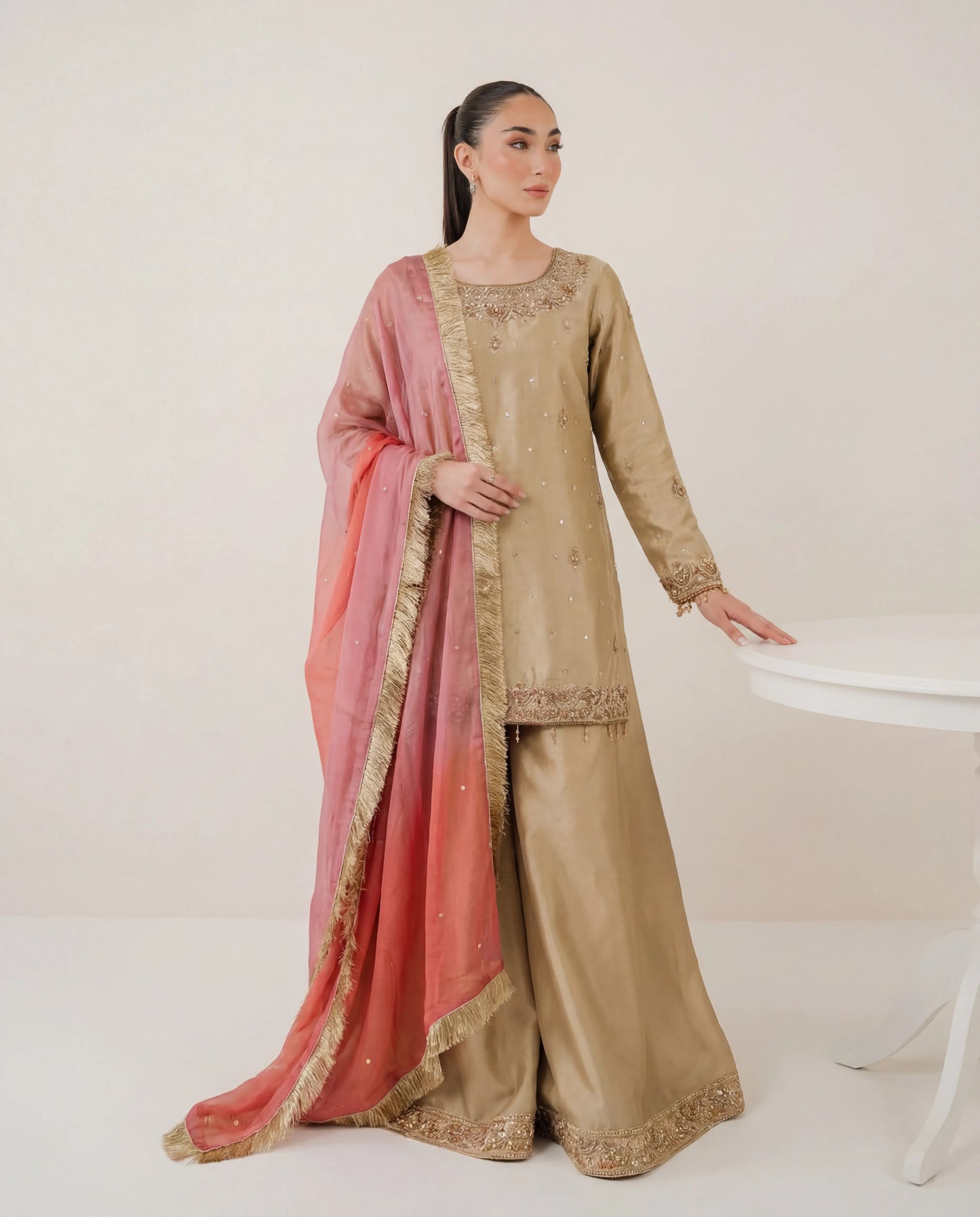 Woman wearing a traditional outfit with a pink dupatta on a white background