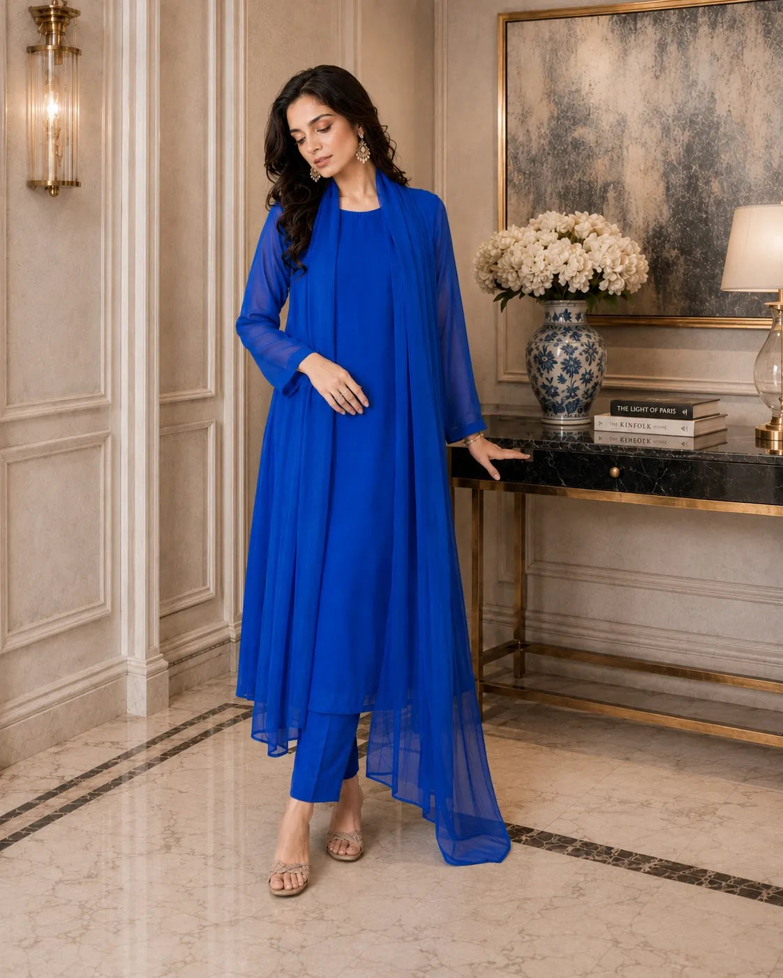 Woman in a blue dress standing in an elegant room with decor elements.