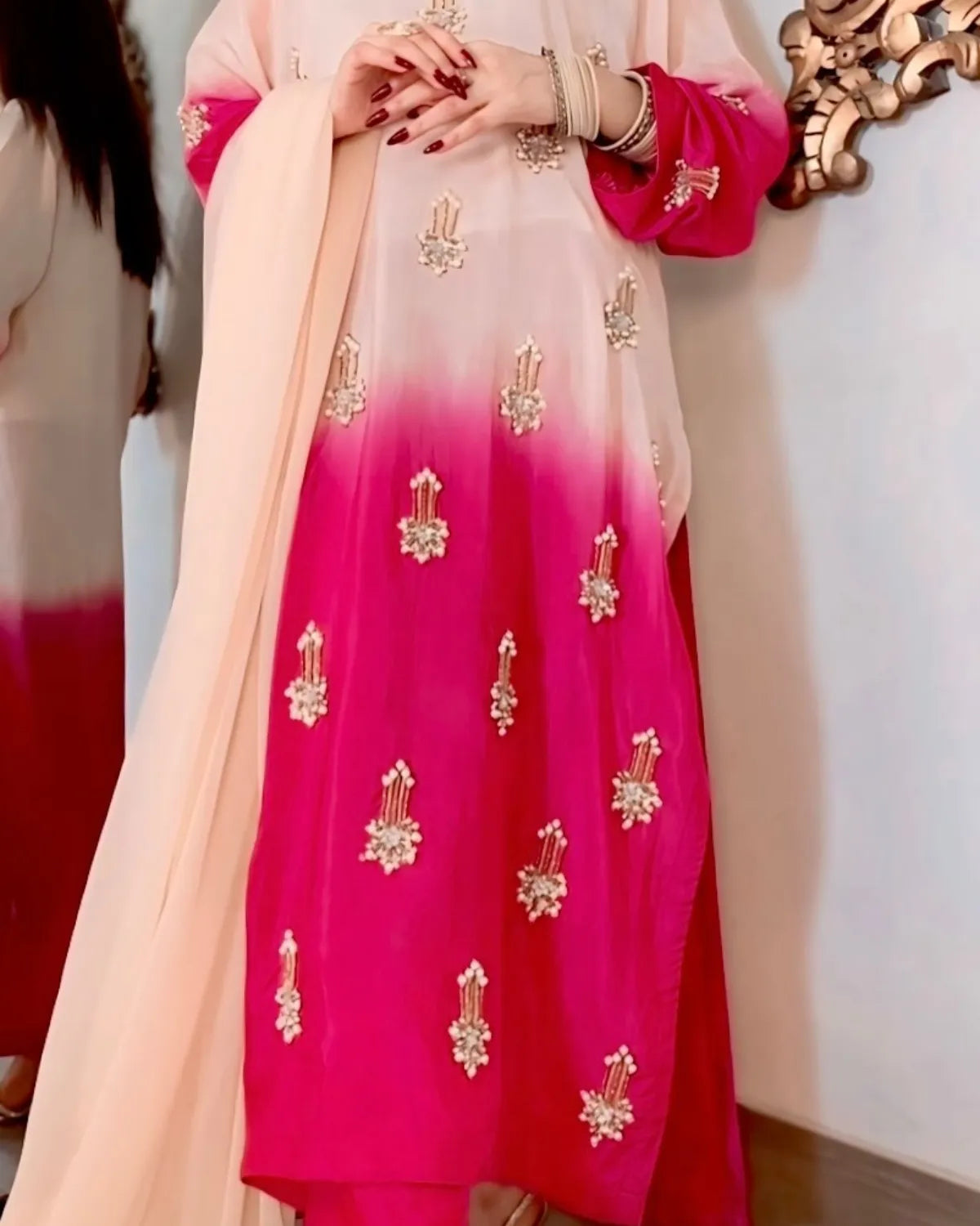 Pink and beige traditional outfit with gold embroidery, held by a person.