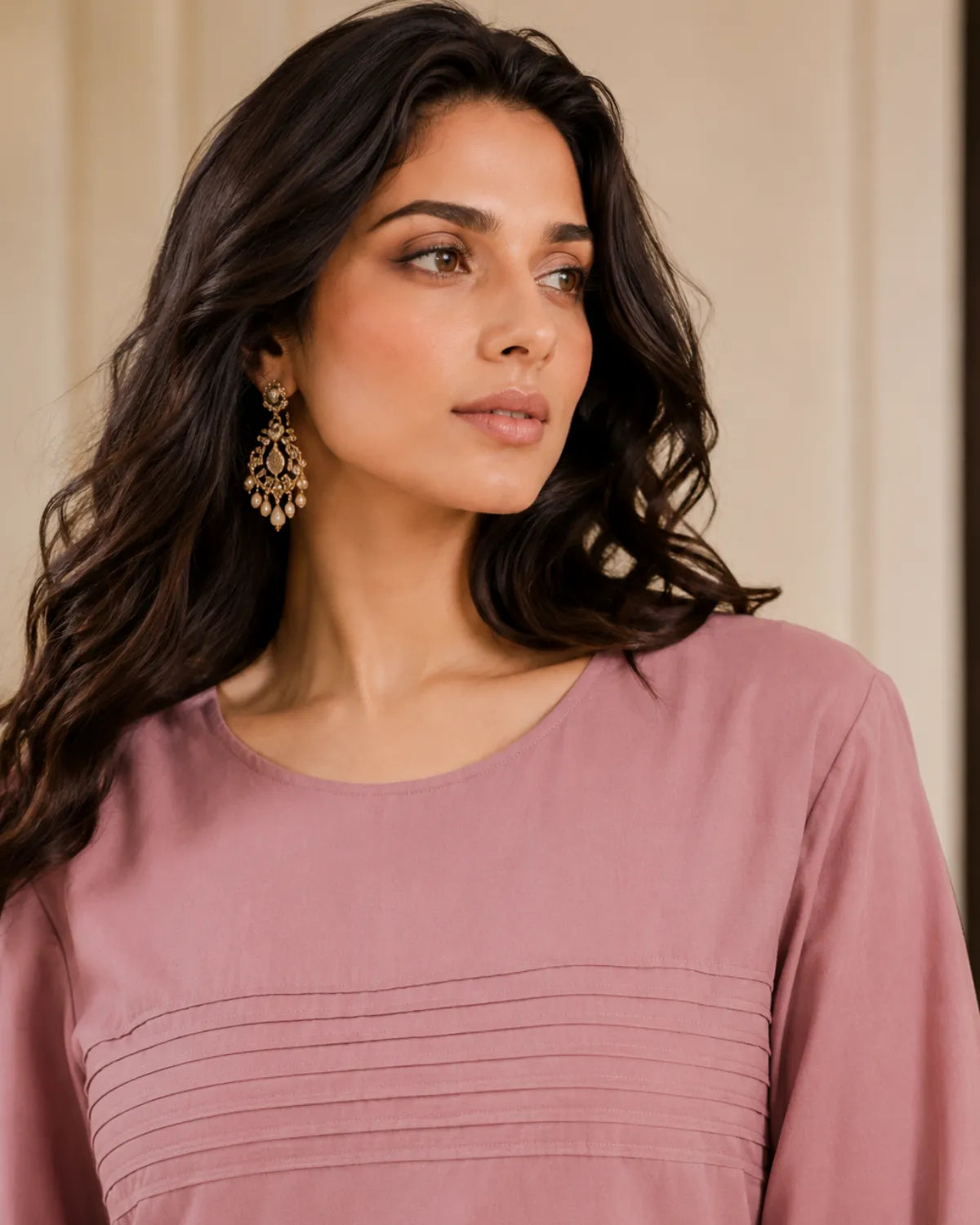 Woman wearing a mauve top with a neutral background