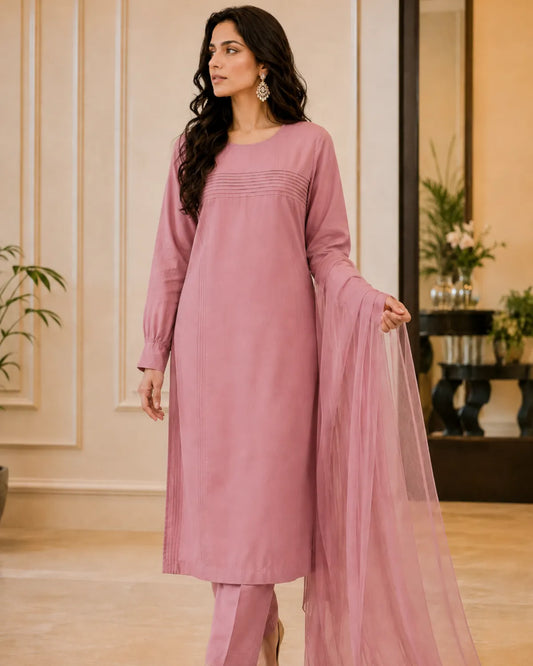 Woman in a pink traditional outfit standing in an elegant room.
