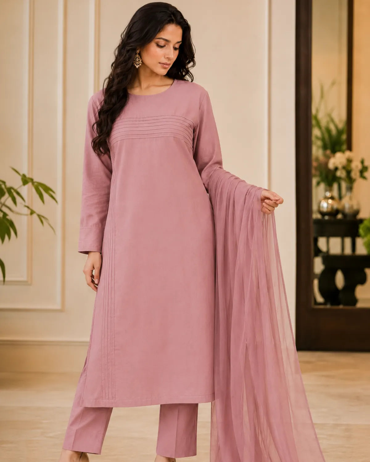 Woman wearing a pink traditional outfit with a dupatta in an indoor setting.
