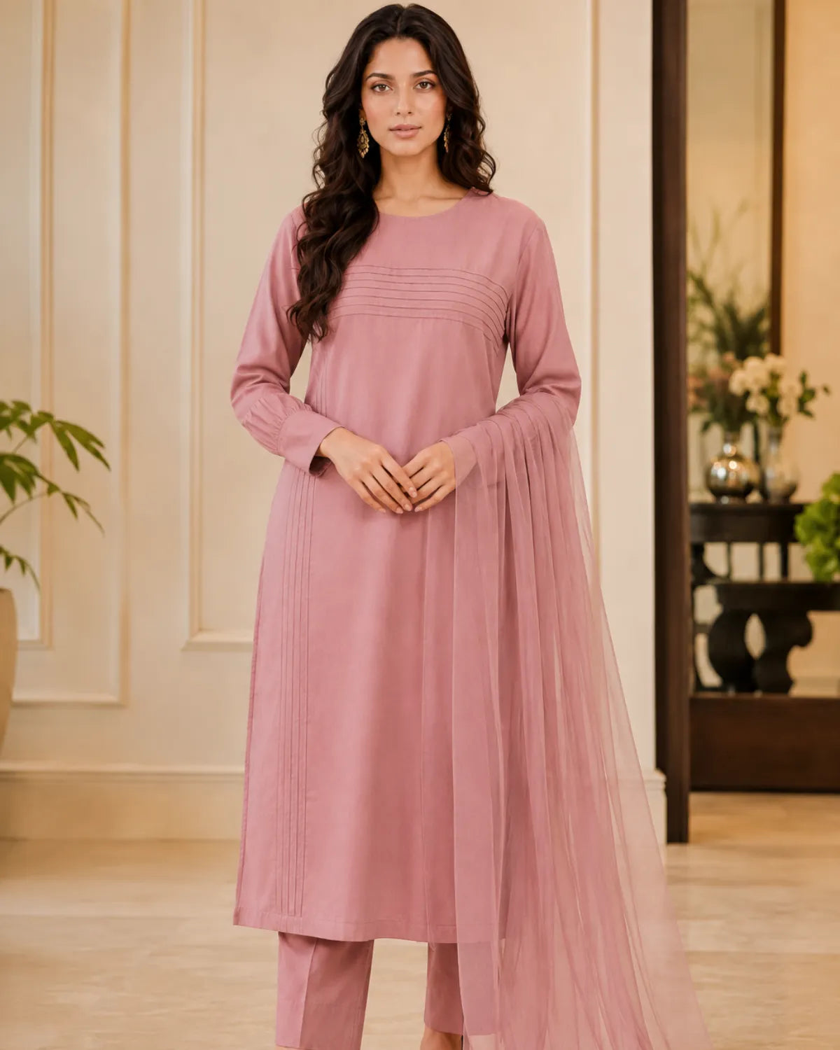 Woman wearing a pink traditional outfit with a sheer dupatta in an indoor setting.