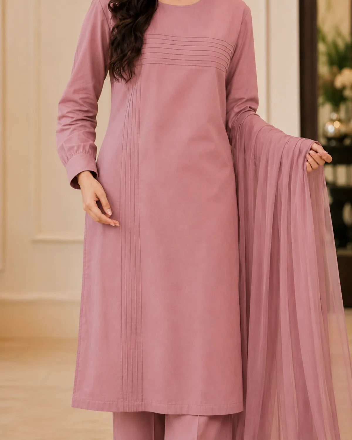 Person wearing a mauve traditional outfit with a matching dupatta.