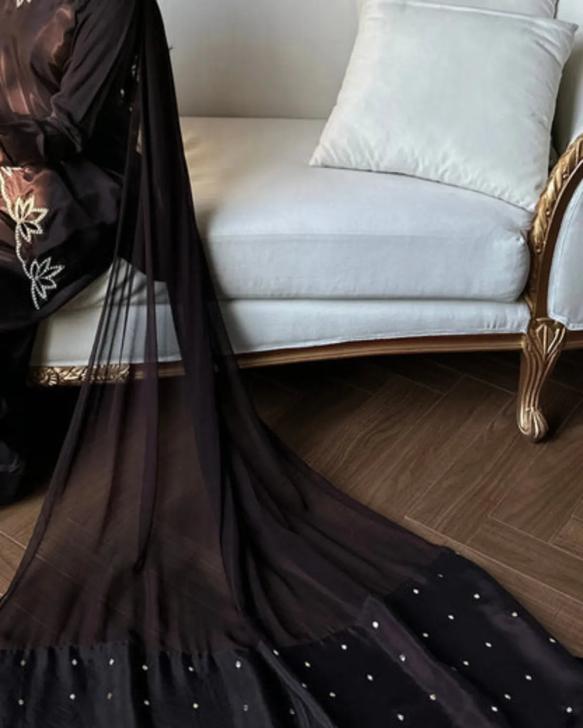Black saree with white polka dots on a white sofa with gold accents