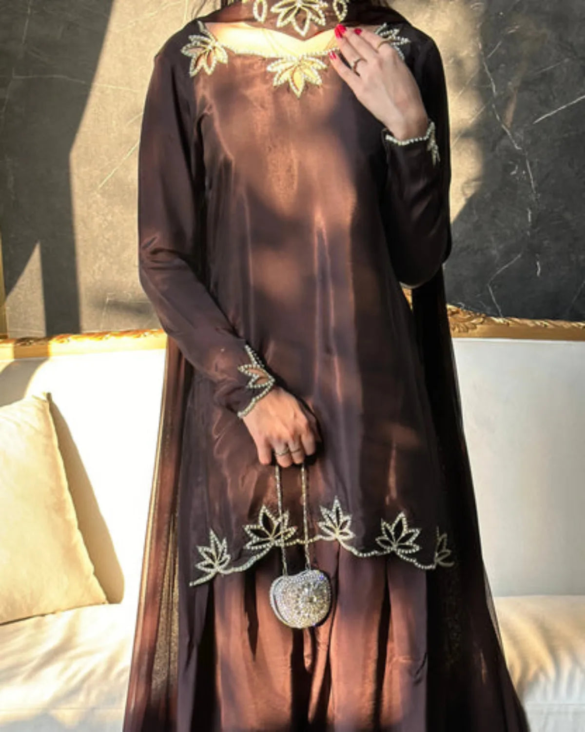 Brown dress with floral embroidery and a heart-shaped brooch on a neutral background