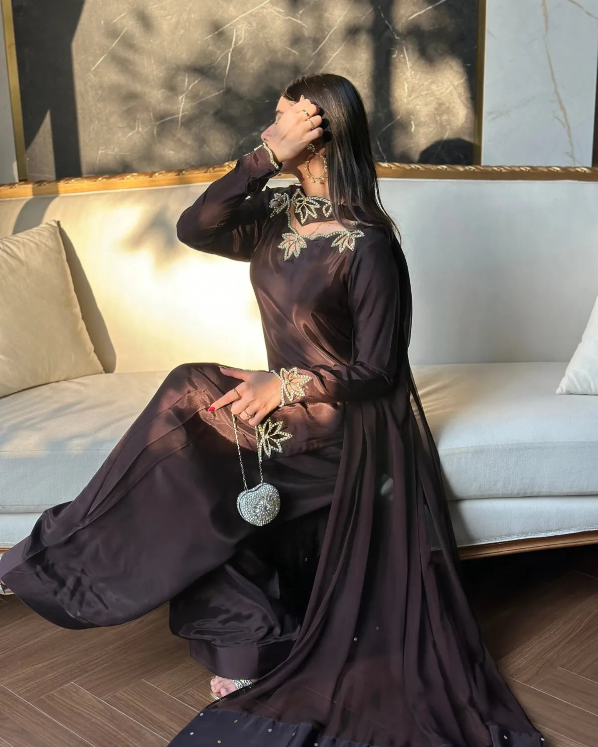 Woman in a dark dress sitting on a couch with a decorative pillow.