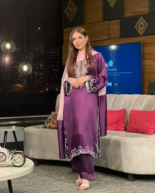 Woman in a purple traditional outfit standing in a modern living room.