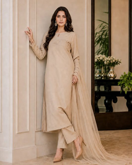 Woman in a beige traditional outfit standing indoors with decor elements in the background