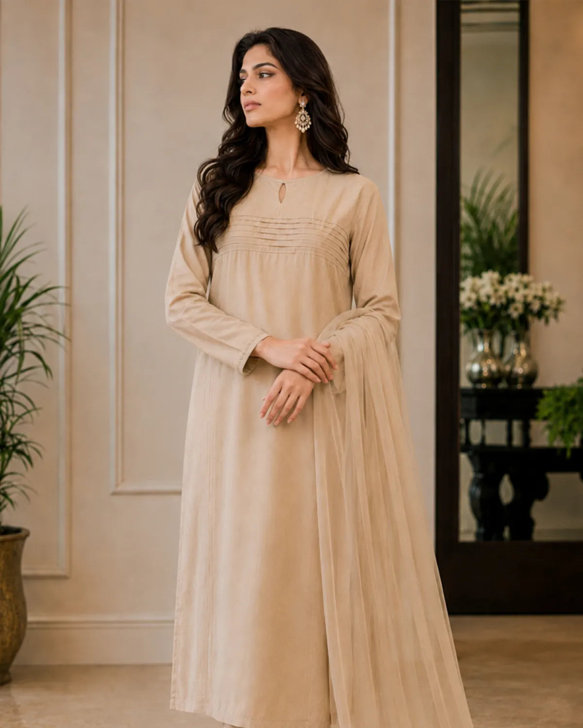 Woman wearing a beige dress standing in a room with decorative elements.