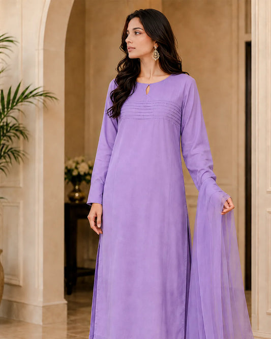 Woman wearing a long purple dress standing in an elegant interior setting.