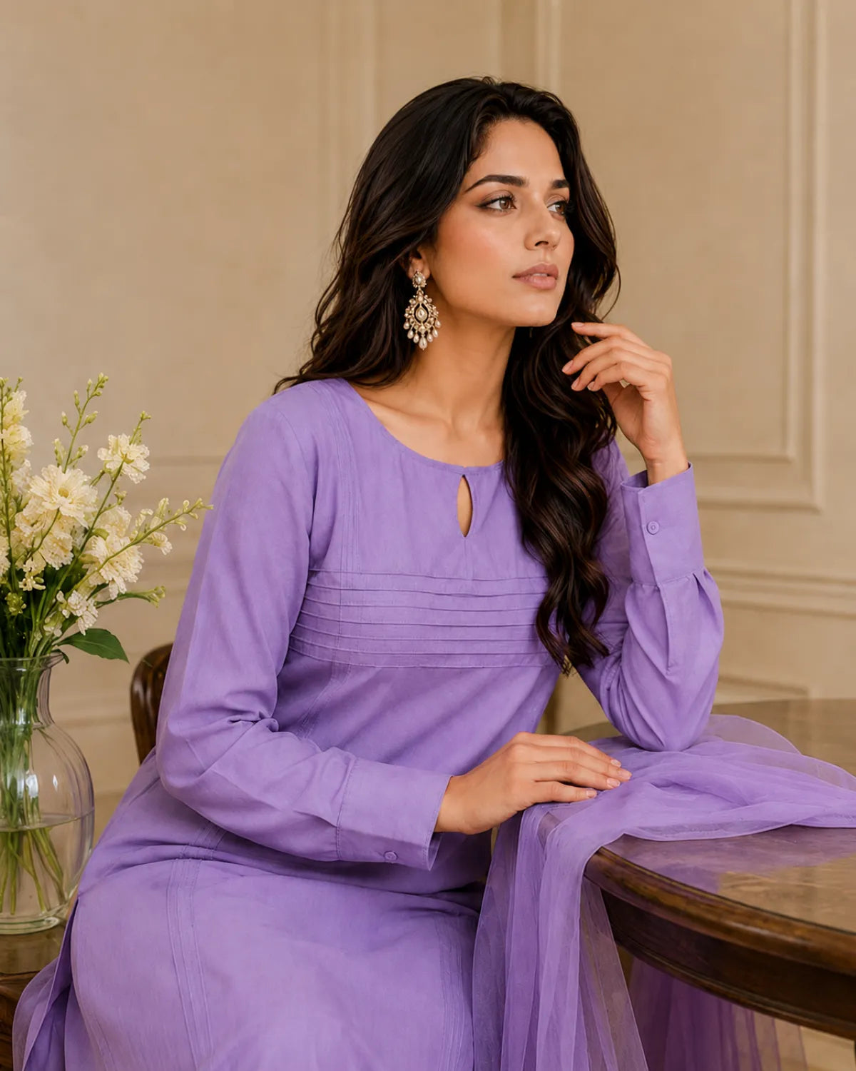 Woman in a purple dress sitting at a table with flowers in the background