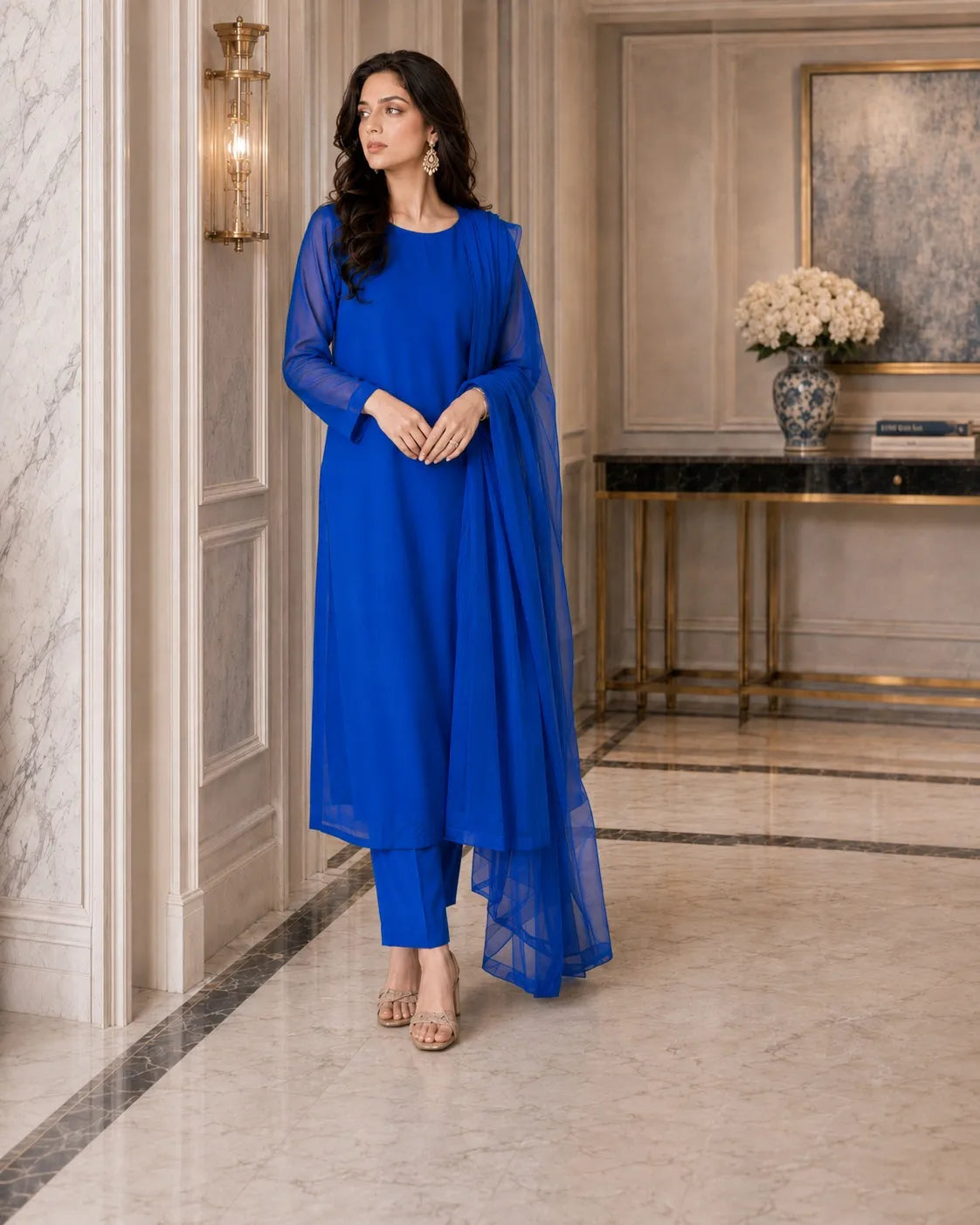 Woman in a blue outfit standing in an elegant interior setting