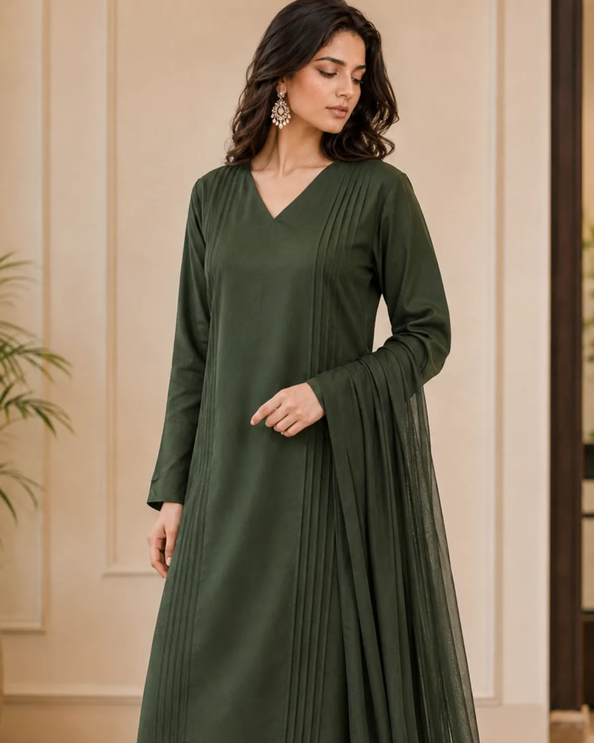 Woman wearing a green dress against a beige wall.