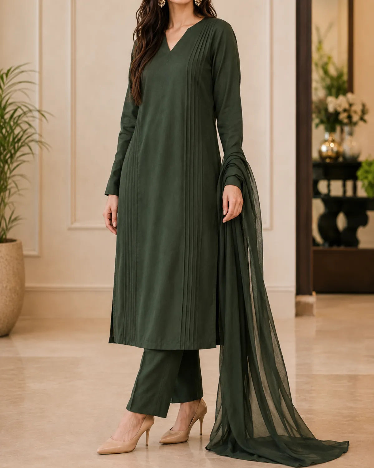 Woman wearing a green traditional outfit with a dupatta in an indoor setting.