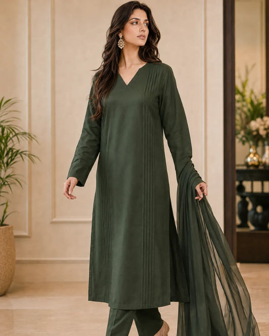 Woman wearing a green outfit with a sheer dupatta in an indoor setting